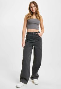 Gray cropped tank top, high-waisted black jeans, wide-leg fit, denim texture, front pockets, styled with white sneakers.
