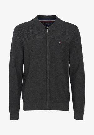 Sivi pleteni kardigan s patentnim zatvaranjem sprijeda, teksturiranim gornjim panelom, rebrastim rukavima i rubom. Ima malu oznaku s logotipom na lijevoj strani prsnog koša.