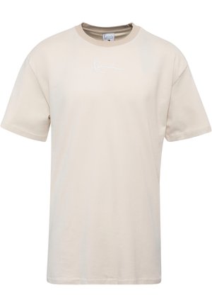 Beżowa bawełniana koszulka z krótkim rękawem, okrągłym dekoltem, z małym białym logo na piersiach i prostym dołem.