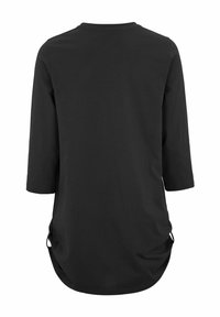 Zwarte tuniek met lange mouwen, afgeronde zoom en zijstrikjes, gezien van achteren op een witte achtergrond.