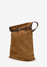 Bolso tote de ante marrón con parte superior enrollada, que presenta un asa de cuero y un detalle de hebilla. Textura suave y diseño simple y funcional.