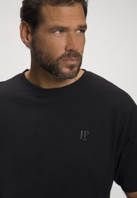 T-shirt nero in cotone con scollatura rotonda e maniche corte. Logo sottile "JP 1880" in grigio sulla parte sinistra del petto.
