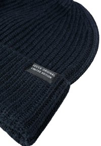 Navy blue knitted beanie with a ribbed texture and a black fabric tag displaying "SOCCX ORIGINAL LIMITED EDITION."