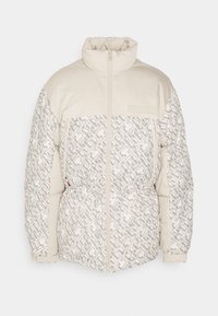 Padded jacket w kolorze beżowym i kremowym o teksturowanym, geometrycznym wzorze. Posiada wysoki kołnierz, zamek błyskawiczny z przodu oraz elastyczny pas.