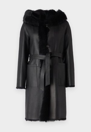 Schwarzer Ledermantel mit einer Kapuze aus Kunstfell, Knopfverschluss und einem Bindegürtel. Verfügt über zwei Fronttaschen und eine weiche Textur entlang der Kanten.