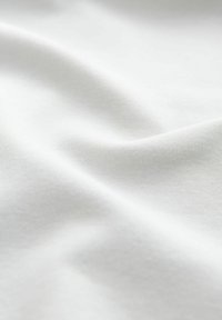 Weißer Baumwollstoff mit einer glatten, weichen Textur, die sanfte Falten und einen subtilen Glanz zeigt, der für hochwertiges Material typisch ist.
