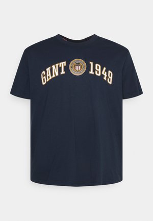 Marineblaues T-Shirt mit kurzen Ärmeln, auf der Brust mit dem Schriftzug "GANT 1949" und einem runden Emblem mit Schild und Lorbeerkranz.