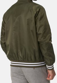 Veste bomber vert olive à finition lisse, avec des poignets et une ceinture élastiques ornés de rayures blanches. Conçue avec un col classique.
