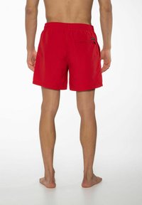 Pantaloni da bagno rossi con cintura elastica e tasca posteriore, caratterizzati da una texture liscia e un design semplice.