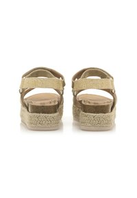 Sandalias de esparto en color beige con suela de yute trenzado, correas ajustables y acentos metálicos. Plantilla interna lisa con una textura sutil.