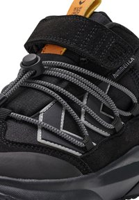 Schwarzer Sportschuh mit texturiertem Obermaterial, elastischen grauen Schnürsenkeln, verstellbarem Riemen und einer eleganten synthetischen Sohle. Mit grauen Akzenten versehen.