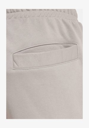 Pantalons de survêtement gris clair avec une petite poche insérée à l'arrière, fabriqués en tissu doux en mélange de coton avec une texture lisse.
