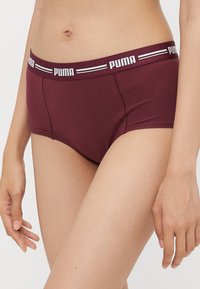 Burgundske hipsterske hlačke z belim elastičnim pasom z blagovno znamko. Narejene iz gladkega, raztegljivega materiala, z minimalnimi šivi.
