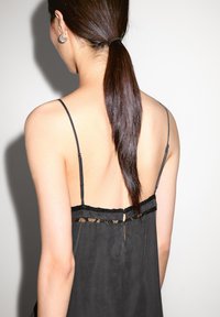Black silk camisole with lace trim, adjustable straps, open back, and a small fabric-covered button detail at the rear.