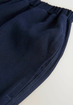 Marineblauwe stoffen shorts met een elastische tailleband, met een zachte textuur en contrasterende stikdetails langs de zijkanten.