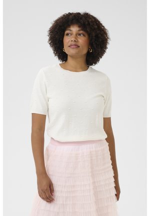 Weißer Kurzarmpullover mit strukturierten Bobble-Akzenten, kombiniert mit einem mehrlagigen rosa Tüllrock. Mit schlichtem Rundhalsausschnitt und figurbetonten Ärmeln.