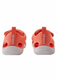 Coral slip-on water shoes with breathable fabric, open sides, white rubber soles, and reinforced heel tabs. Logo displayed on heel.