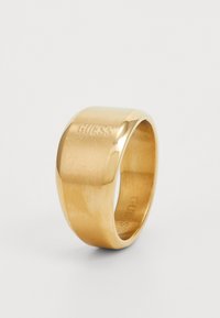 Gold-toned ring with a polished, smooth surface. Features an embossed "GUESS" logo on one side. Rounded band design.