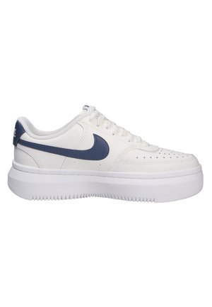Zapatillas de cuero blancas con puntera redondeada, acentos en azul marino, cordones planos texturizados y una gruesa suela de goma blanca con un dibujo en la banda de rodadura.