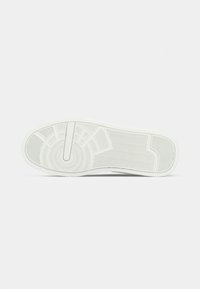 White sneaker sole with circular and zigzag tread patterns on a plain light background.