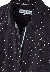 Chemise noire à pois blancs, design avec col, fermeture à boutons, dotée d'un patch logo brodé avec des strass sur la poche poitrine.