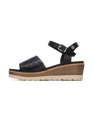 Sandalias cuña de cuero negro con parte superior perforada, correa ajustable para el tobillo y base de color claro con textura similar a la madera.