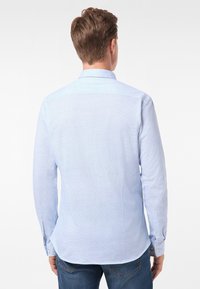 Jasnoniebieska koszula z długim rękawem, o sztywnym kołnierzyku, z guzikami na mankietach i teksturowanym materiałem. Dopasowany krój z zaokrąglonym dołem, zaprojektowana z myślą o casualowym stylu.