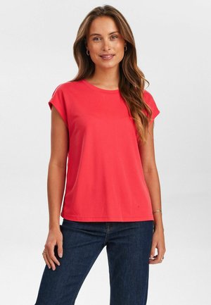 Korallfarbenes T-Shirt mit kurzen Ärmeln, Rundhalsausschnitt und lockerer Passform, kombiniert mit dunkelblauen Jeans. Weicher Stoff und minimalistisches Design.