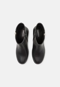 Botas negras hasta el tobillo hechas de cuero suave. Punta redonda, tacón bajo, con un cierre de cremallera en el lateral. El interior cuenta con un forro suave.