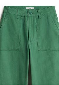 Pantalons en coton verts au toucher lisse, avec deux poches avant, une fermeture à bouton et un design ajusté.