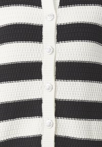 Svart- och vitrandig kofta i strukturerad stickad kvalitet, med fem runda silverknappar fram.