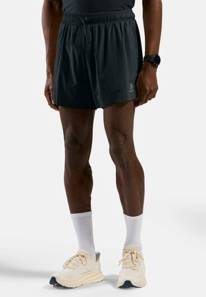 Dark athletic shorts with an elastic waistband, featuring a logo on the side. Worn with light sneakers and white crew socks.