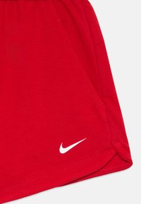Shorts de sport rouges avec une taille élastique, des poches latérales et un logo Nike blanc sur l'ourlet gauche. Matière douce et respirante.