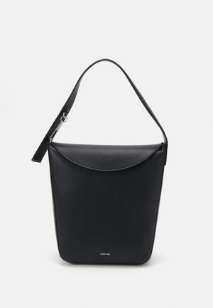 Sac à main en cuir noir Calvin Klein avec un unique rabat incurvé et une bandoulière amovible, présenté sur un fond uni clair.