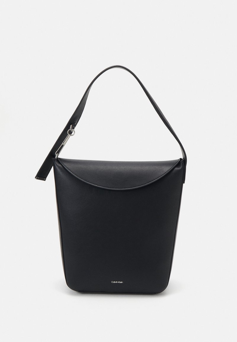 Sac à main en cuir noir Calvin Klein avec un unique rabat incurvé et une bandoulière amovible, présenté sur un fond uni clair.