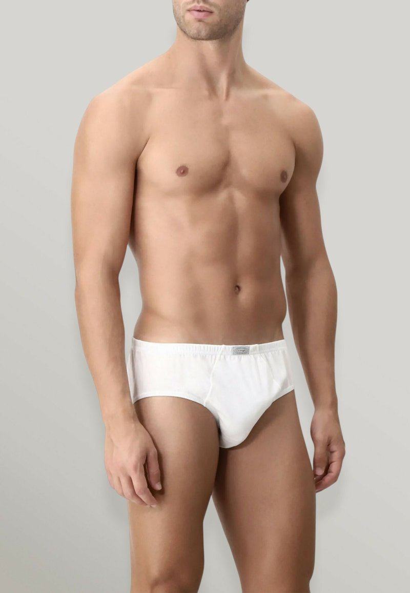 Slip di cotone bianco con elastico in vita, texture liscia e senza motivi visibili, indossati da un modello su uno sfondo neutro.