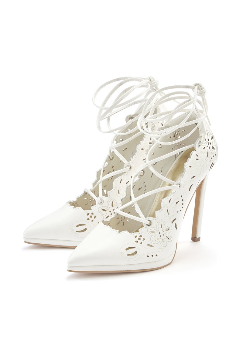 White high-heeled shoes with pointed toes, lace-up design, and floral cutouts along the sides, featuring a smooth leather texture.