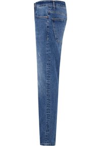 Jean skinny en denim bleu moyen, arborant un design à cinq poches, des accents cousus et une légère décoloration sur les jambes pour plus de texture.