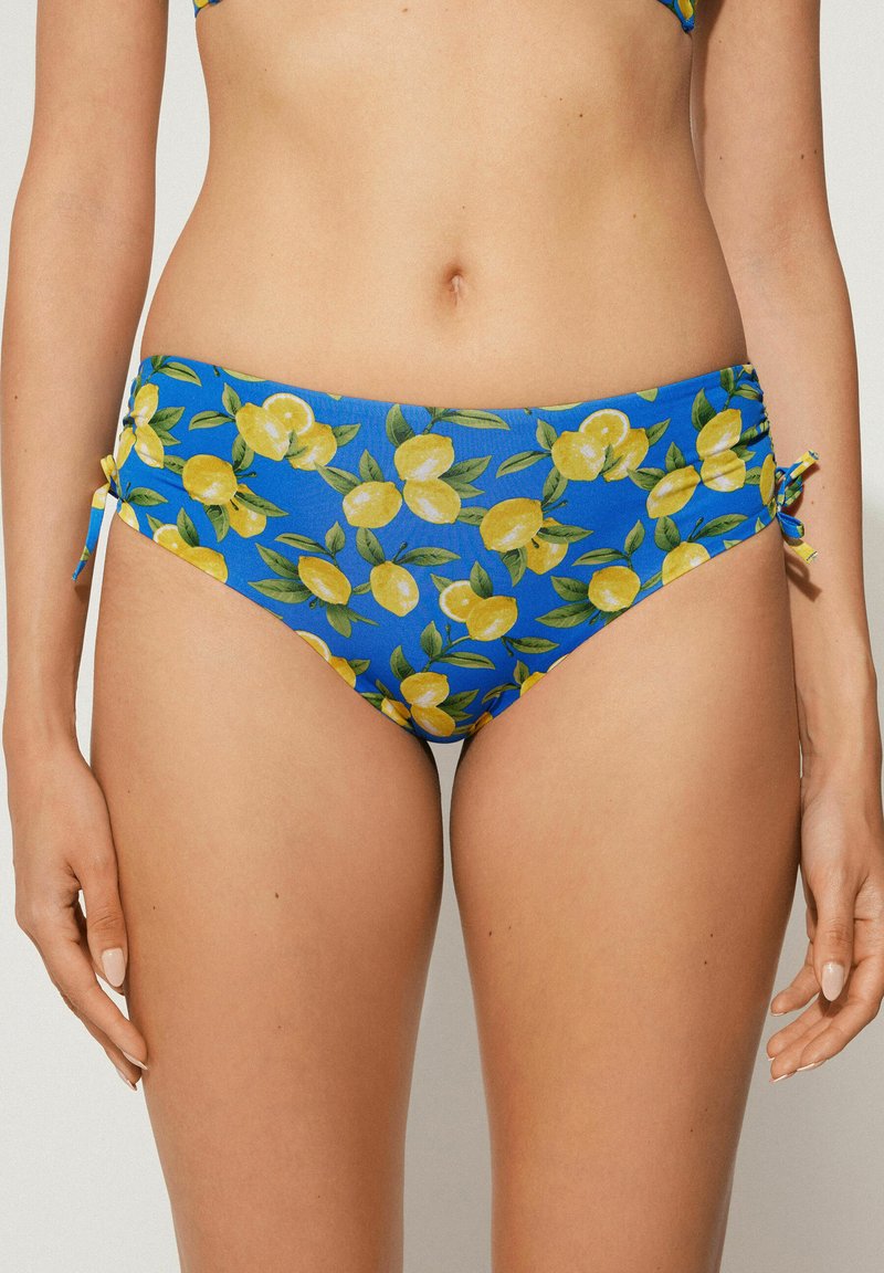 Modré bikini kalhotky s potiskem citronů, designem na zavázání po stranách a měkkou, texturovanou tkaninou s živými zelenými listy a žlutými citrony.