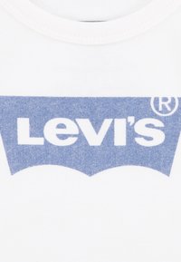 T-shirt bianco in cotone con logo blu Levi's caratterizzato da una curva distintiva nella parte inferiore, texture morbida e scollo a costine.