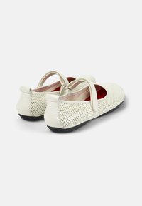 Scarpe Mary Jane in pelle bianca forata con punta tonda, cinturino regolabile e suola in gomma nera. Fodera interna rossa.
