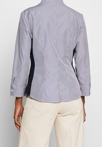 Randig skjorta med knappar i marinblått och vitt med långa ärmar, med en skräddarsydd passform och sidopaneler i en enfärgad nyans.