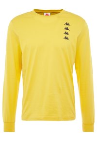 Gelbes Langarmshirt mit Rundhalsausschnitt und vier kleinen schwarzen Logos, die vertikal auf der linken Brustseite gestapelt sind.