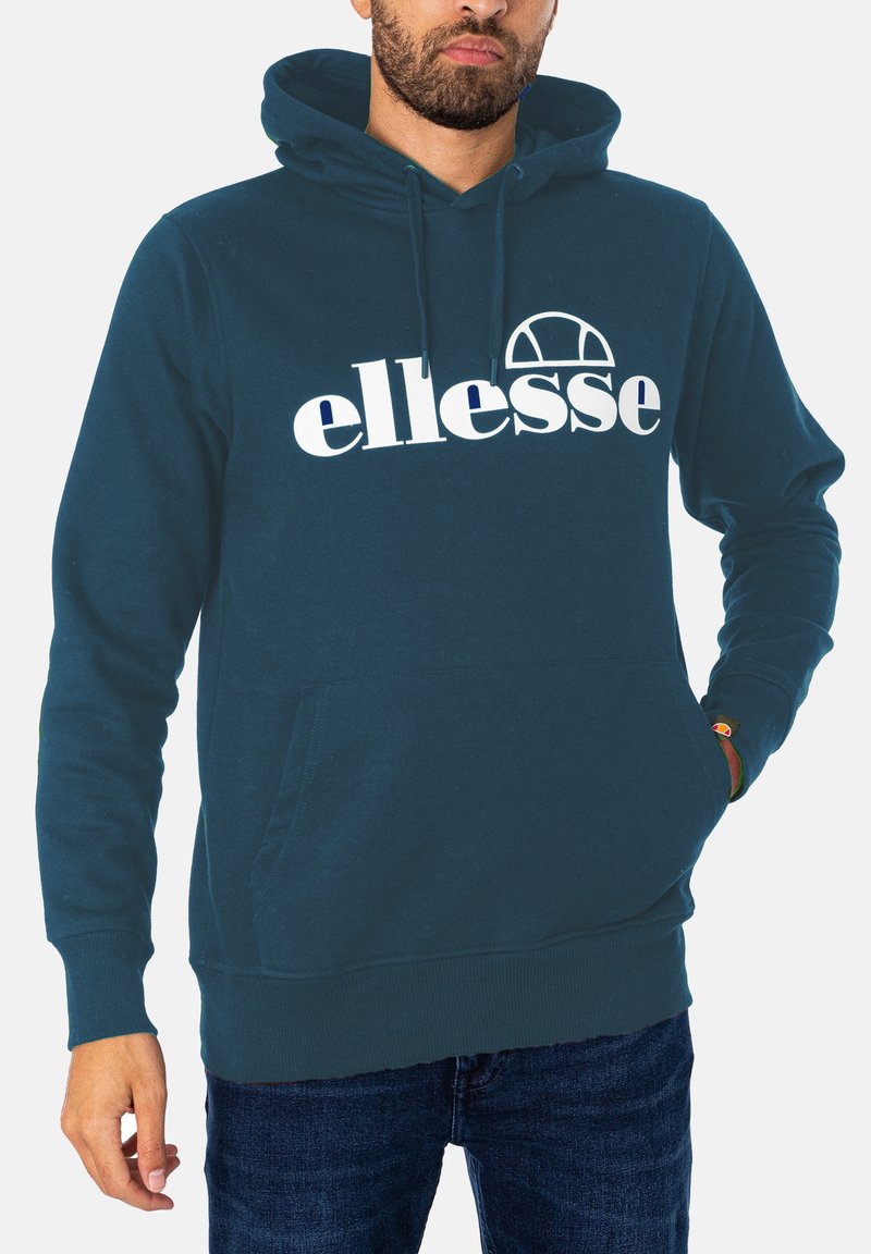 Teal Kapuzenpullover mit einer Fronttasche, gerippten Bündchen und Saum sowie einem auffälligen weißen Logo, das über der Brust aufgedruckt ist. Material aus Baumwollmischung.