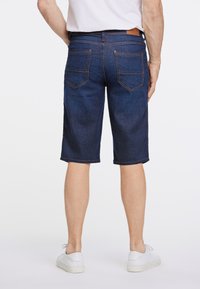 Pantalones cortos de mezclilla oscuros para hombre con un corte recto, que cuentan con cinco bolsillos, costuras en contraste y una etiqueta de cuero en la cinturilla.
