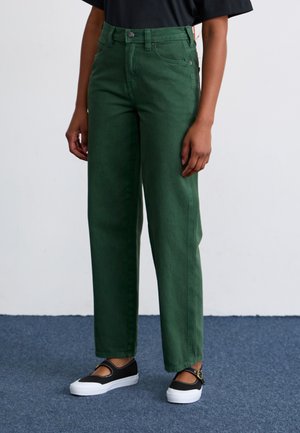 Jean en coton vert taille haute à jambes larges, avec fermeture à bouton, poches avant et texture lisse. Assorti avec des chaussures noires.