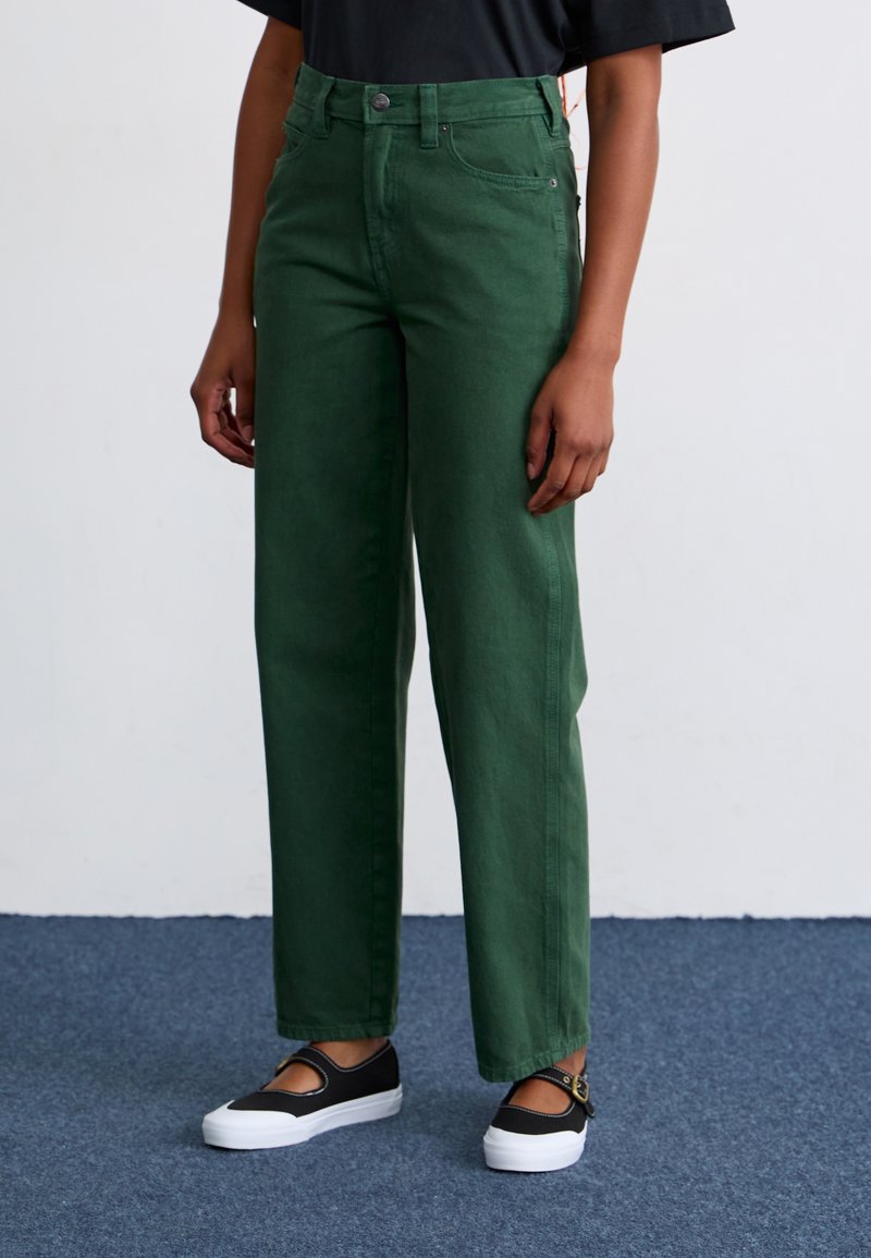 Green high-waisted wide-leg jeans made of cotton, featuring a button closure, front pockets, and a smooth texture. Worn with black shoes.