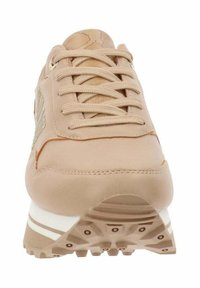 Sneaker beige chiaro con lacci frontali, materiale testurizzato e dettagli di design sottili sui lati. Presenta una suola con strisce bianche e battistrada in gomma.