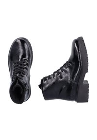 Bottines en cuir verni noir avec une semelle épaisse, un bout rond, un laçage à l'avant et des œillets métalliques. Texture lisse avec une finition brillante.