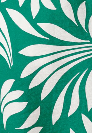 Motifs de feuilles tropicales blanches sur un fond de tissu vert vif, montrant un dessin botanique audacieux et abstrait.